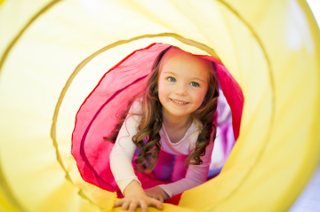 Mädchen in einem gelben Spieltunnel